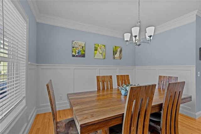 dining room featuring ornamental molding, light wood-type flooring, and an inviting chandelier