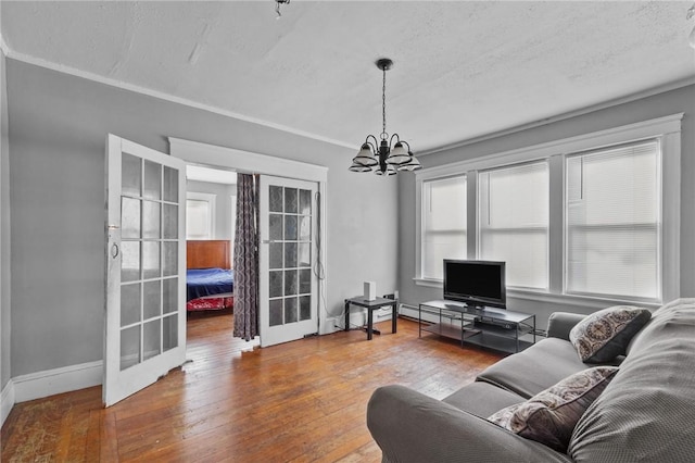 living room with french doors, ornamental molding, a textured ceiling, hardwood / wood-style flooring, and a notable chandelier