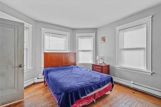 bedroom with a baseboard radiator and light hardwood / wood-style floors