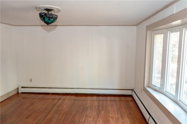 unfurnished room with baseboard heating, wood-type flooring, and ornamental molding