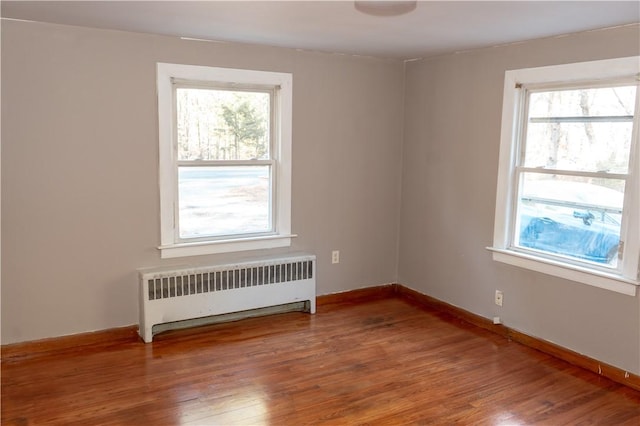 spare room featuring radiator heating unit, a healthy amount of sunlight, and wood-type flooring