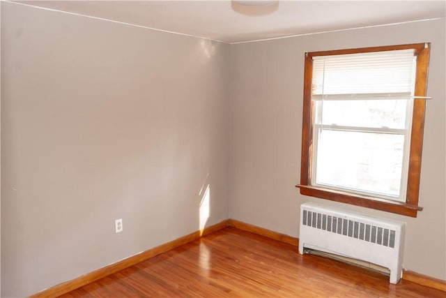 empty room featuring radiator and light hardwood / wood-style flooring