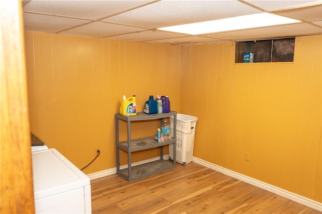 clothes washing area featuring wood-type flooring, washing machine and dryer, and wooden walls