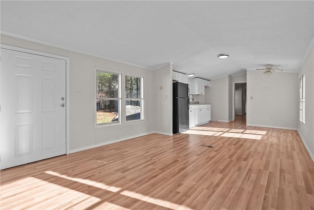 unfurnished living room featuring ceiling fan, light hardwood / wood-style floors, crown molding, and vaulted ceiling