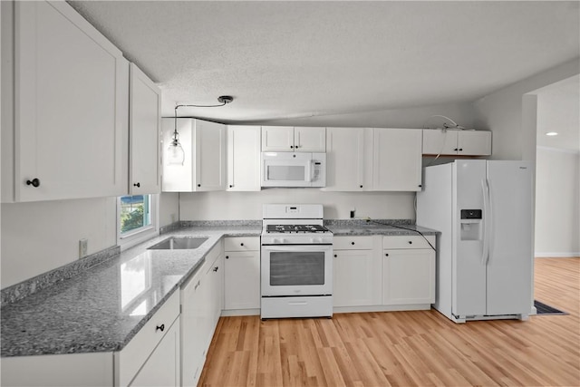 kitchen with dark stone countertops, white cabinetry, light hardwood / wood-style flooring, and white appliances