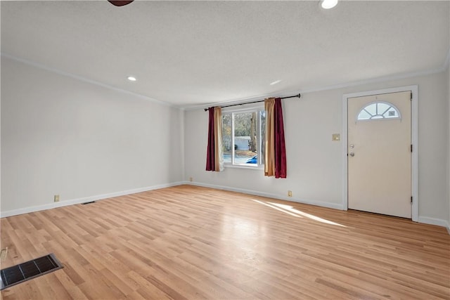 entryway with a textured ceiling, light wood-type flooring, and crown molding