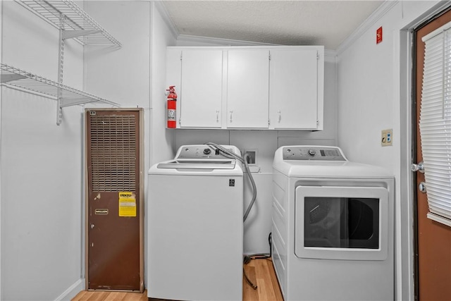 clothes washing area featuring cabinets, independent washer and dryer, a textured ceiling, ornamental molding, and light hardwood / wood-style floors