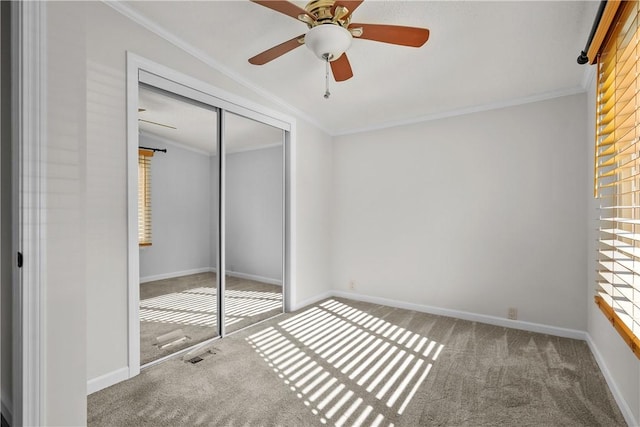 unfurnished bedroom featuring carpet, a closet, crown molding, and ceiling fan