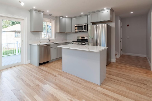 kitchen featuring a center island, stainless steel appliances, sink, hanging light fixtures, and gray cabinets