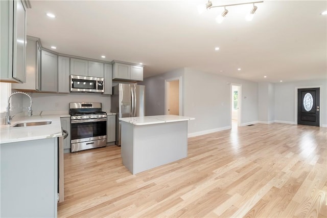 kitchen with gray cabinets, a center island, sink, light hardwood / wood-style flooring, and appliances with stainless steel finishes