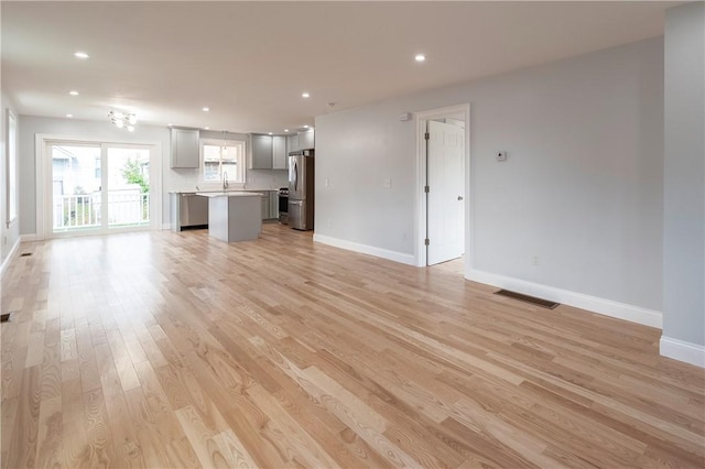 unfurnished living room with sink and light hardwood / wood-style flooring