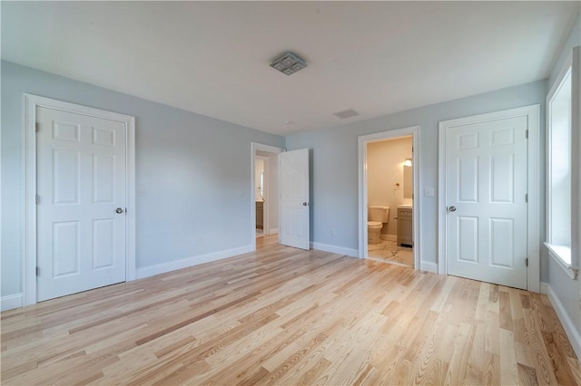 unfurnished bedroom featuring light wood-type flooring and connected bathroom