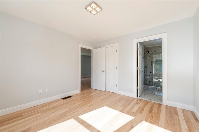 unfurnished bedroom featuring a closet, ensuite bathroom, and hardwood / wood-style floors