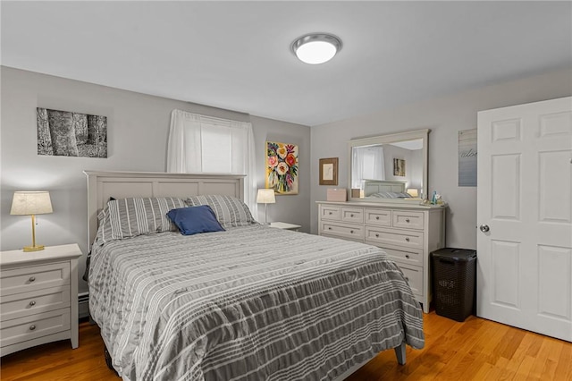 bedroom featuring light hardwood / wood-style flooring and a baseboard heating unit