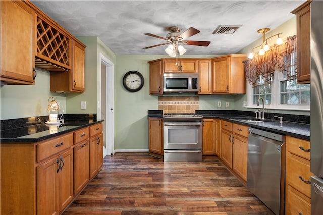 kitchen with ceiling fan, backsplash, sink, dark wood-type flooring, and stainless steel appliances