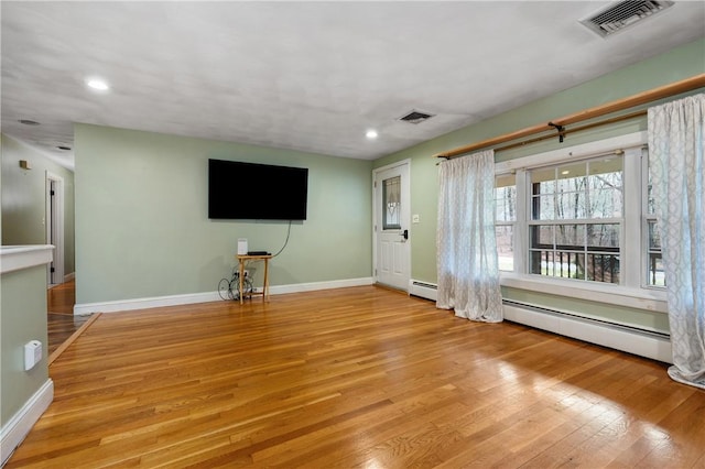 unfurnished living room with light hardwood / wood-style floors and a baseboard heating unit