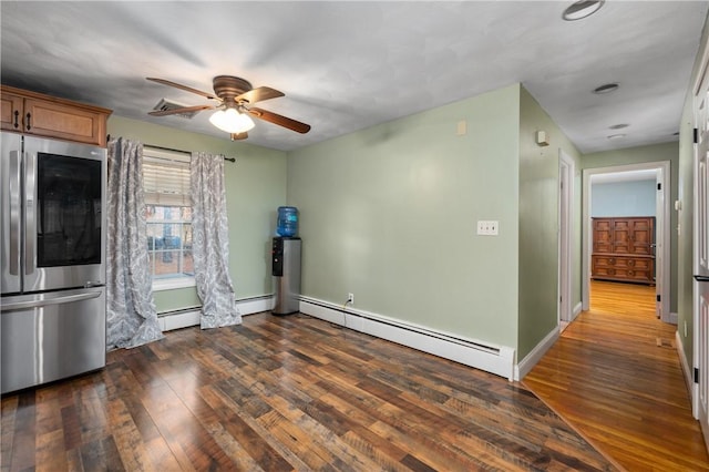 interior space featuring dark wood-type flooring, a baseboard heating unit, stainless steel fridge, and ceiling fan