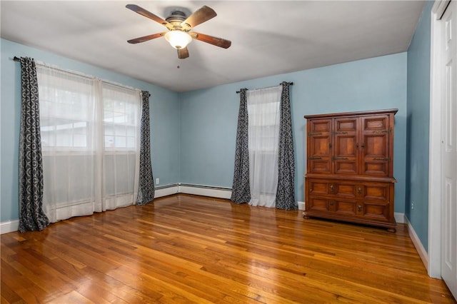 unfurnished bedroom featuring ceiling fan, wood-type flooring, and a baseboard heating unit