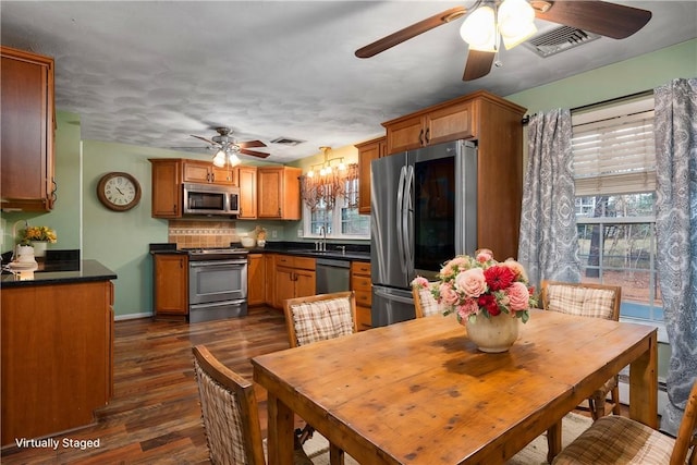 dining area with ceiling fan with notable chandelier, sink, dark hardwood / wood-style flooring, and plenty of natural light