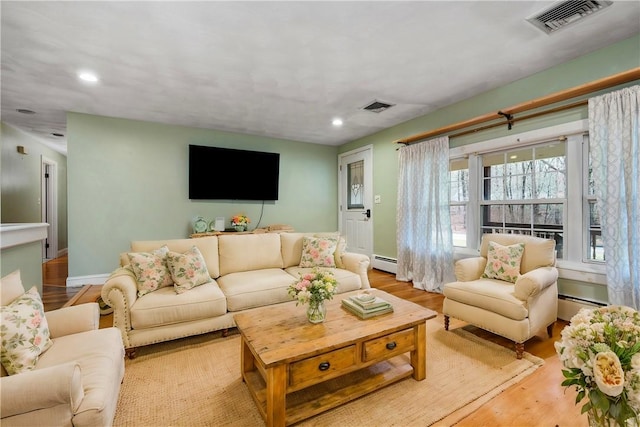 living room with baseboard heating and light hardwood / wood-style flooring