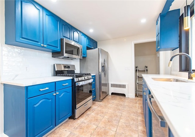 kitchen featuring blue cabinetry, appliances with stainless steel finishes, radiator heating unit, and sink