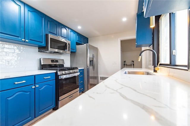 kitchen featuring light stone countertops, appliances with stainless steel finishes, blue cabinets, and sink