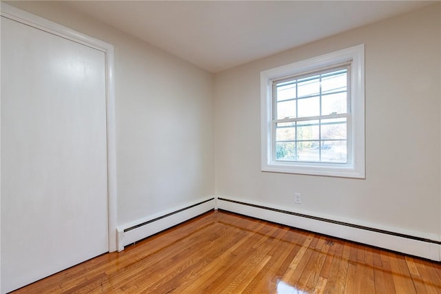 unfurnished room with wood-type flooring and a baseboard heating unit