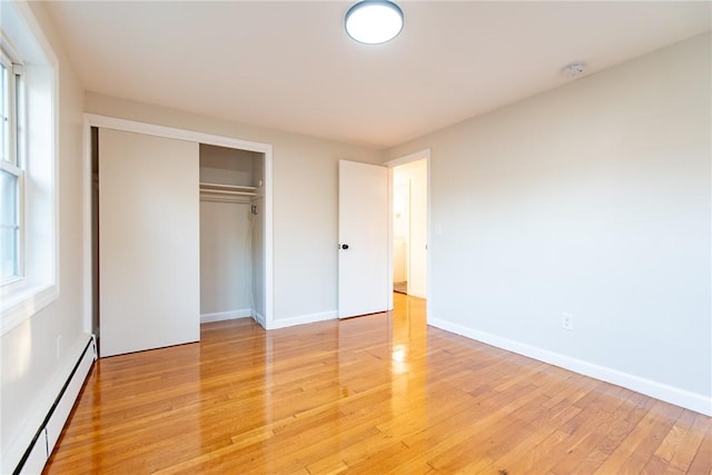 unfurnished bedroom featuring a closet, light hardwood / wood-style floors, and a baseboard radiator