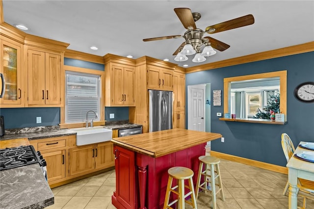 kitchen with sink, stainless steel appliances, a kitchen bar, light tile patterned floors, and ornamental molding