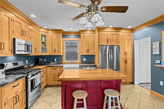 kitchen with a kitchen bar, sink, light tile patterned floors, and appliances with stainless steel finishes