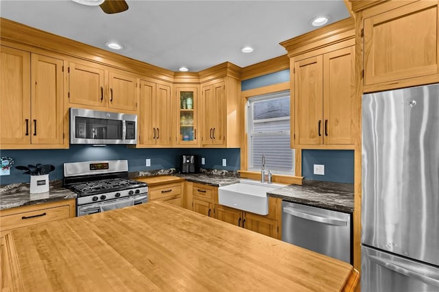 kitchen with stainless steel appliances, ceiling fan, sink, light brown cabinets, and butcher block counters