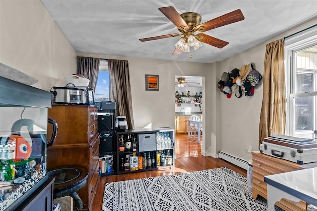 interior space featuring hardwood / wood-style floors, ceiling fan, and a baseboard heating unit