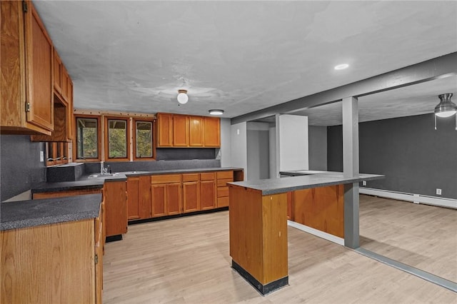 kitchen with light wood-type flooring, a breakfast bar, a baseboard heating unit, sink, and a kitchen island