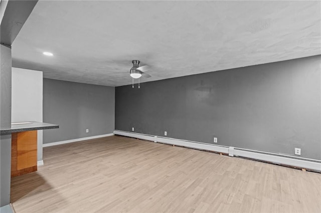 unfurnished living room featuring baseboard heating, ceiling fan, and light hardwood / wood-style flooring