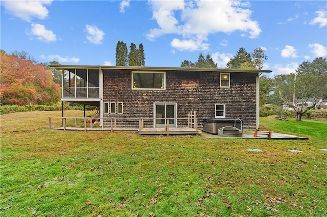 rear view of property with a lawn, a sunroom, a wooden deck, a patio, and a hot tub