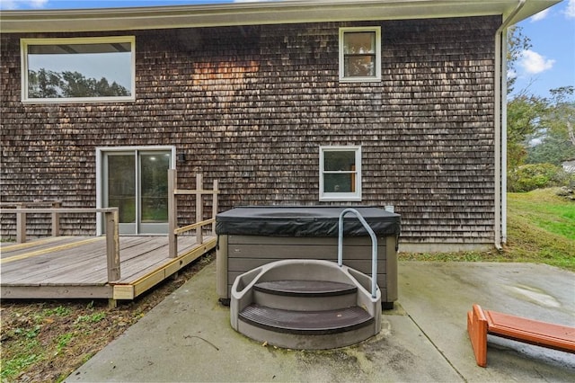 back of property featuring a hot tub, a deck, and a patio area