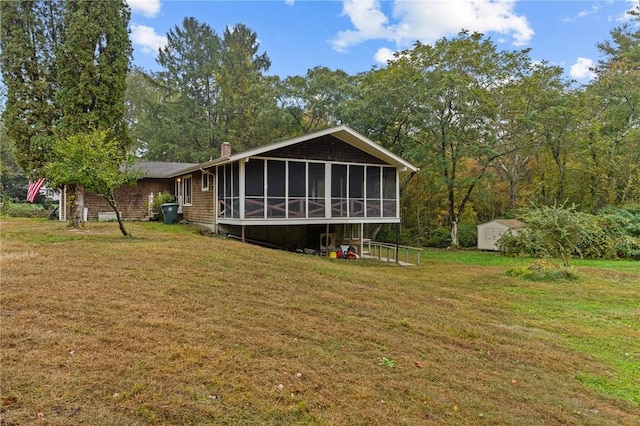 back of house featuring a sunroom, a shed, and a lawn