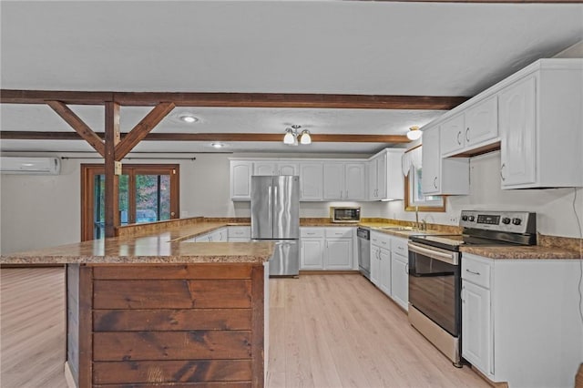 kitchen with white cabinets, an AC wall unit, appliances with stainless steel finishes, beamed ceiling, and kitchen peninsula