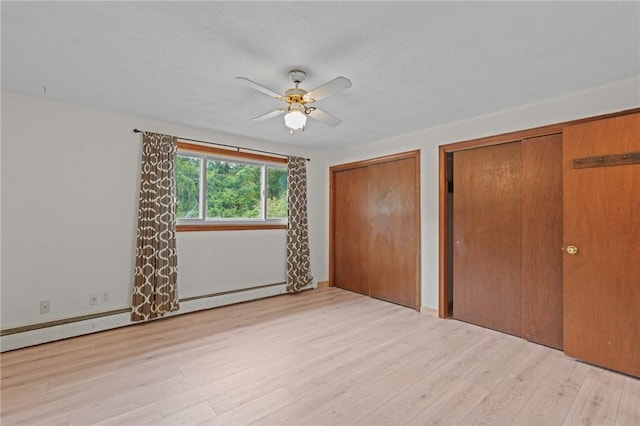 unfurnished bedroom featuring light wood-type flooring, a baseboard radiator, ceiling fan, and multiple closets