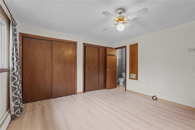 unfurnished bedroom with connected bathroom, ceiling fan, baseboard heating, two closets, and light wood-type flooring