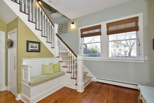 stairs with hardwood / wood-style flooring and a baseboard heating unit