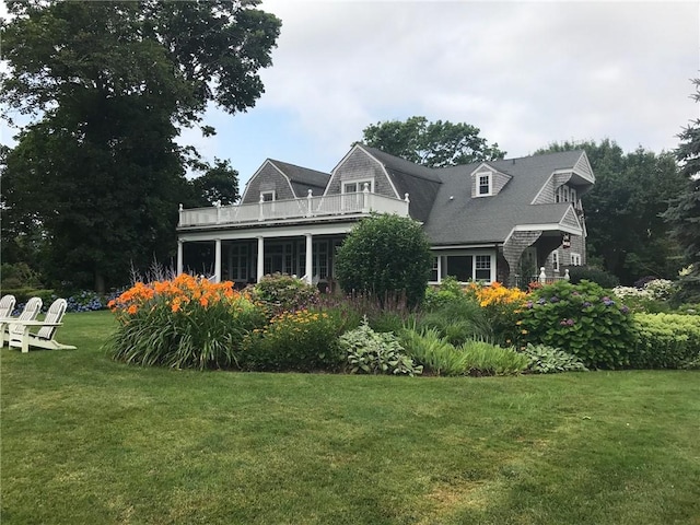 back of house featuring a lawn and a balcony