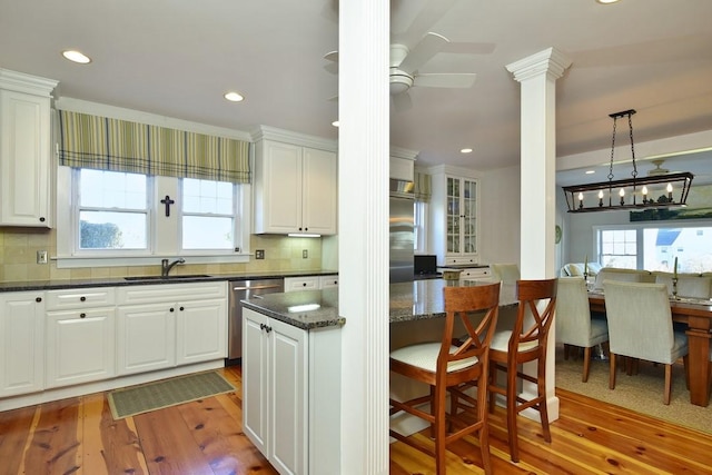 kitchen featuring white cabinets, decorative light fixtures, light wood-type flooring, and stainless steel appliances