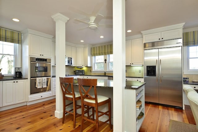 kitchen featuring white cabinets, backsplash, light hardwood / wood-style floors, and stainless steel appliances