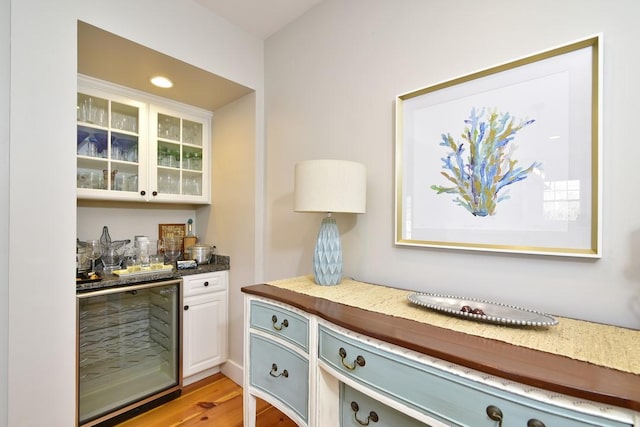 bar with white cabinets, light hardwood / wood-style flooring, and beverage cooler