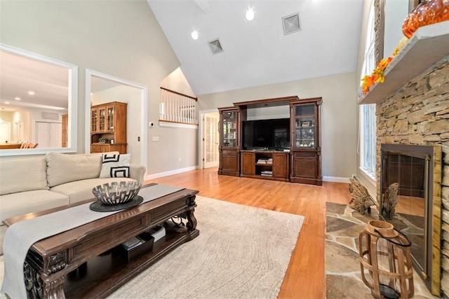 living room with a fireplace, high vaulted ceiling, and light hardwood / wood-style flooring