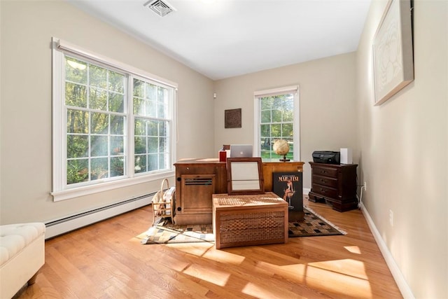 living area with a wealth of natural light, hardwood / wood-style flooring, and baseboard heating