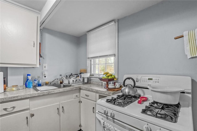 kitchen with white cabinetry, sink, and white range with gas cooktop