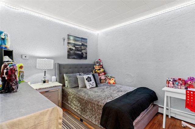 bedroom with dark wood-type flooring and a baseboard heating unit