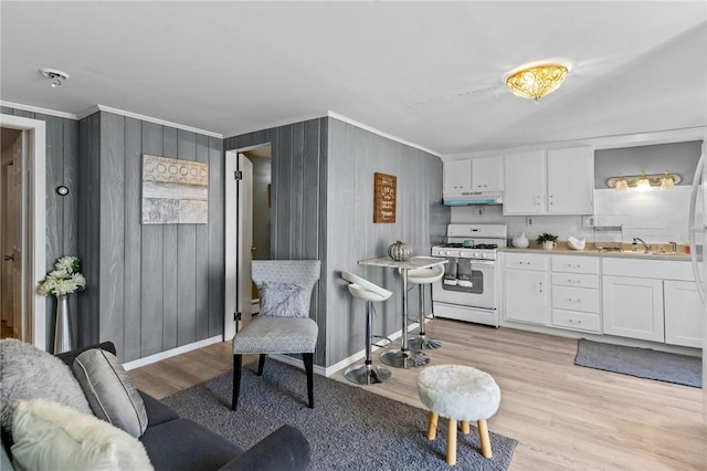 kitchen featuring white cabinetry, sink, light hardwood / wood-style floors, gas range gas stove, and crown molding